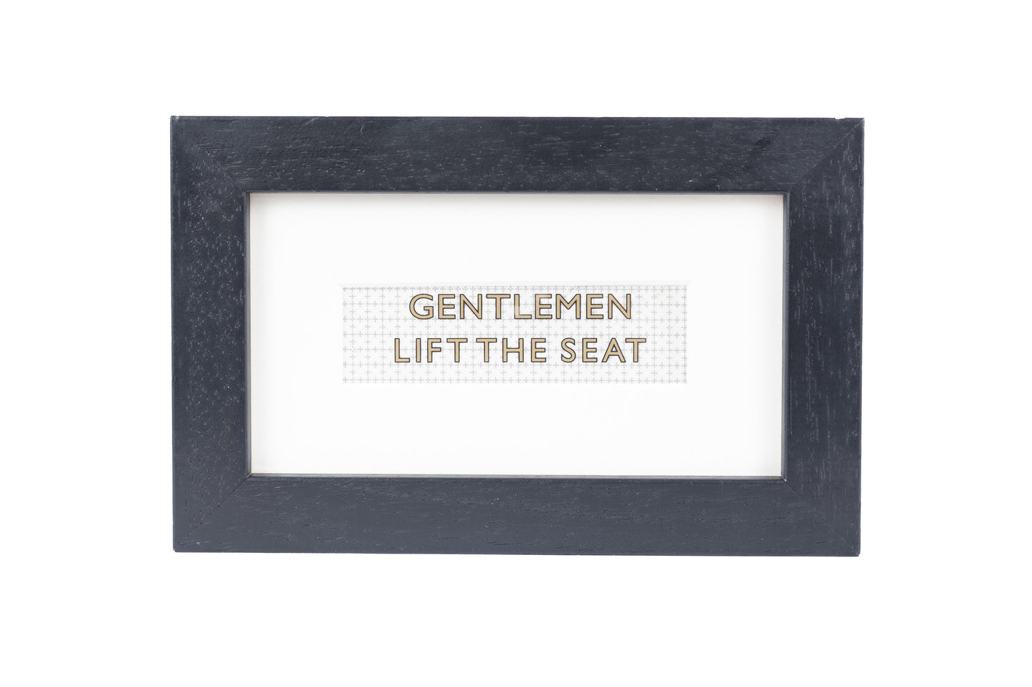 A black frame with a white background and a Gentlemen lift the seat gold text on a small Formica print background