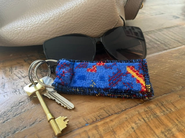 Metroline blue patterned bus moquette keyring beside sunglasses and keys on a wooden table