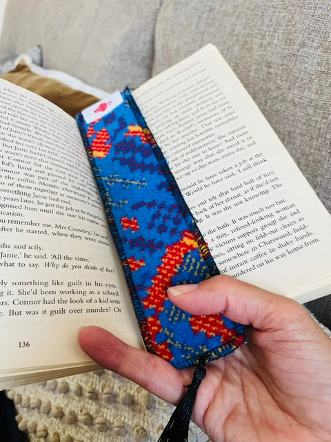 Metroline bus moquette bookmark in blue, red and orange, marking a page in an open book