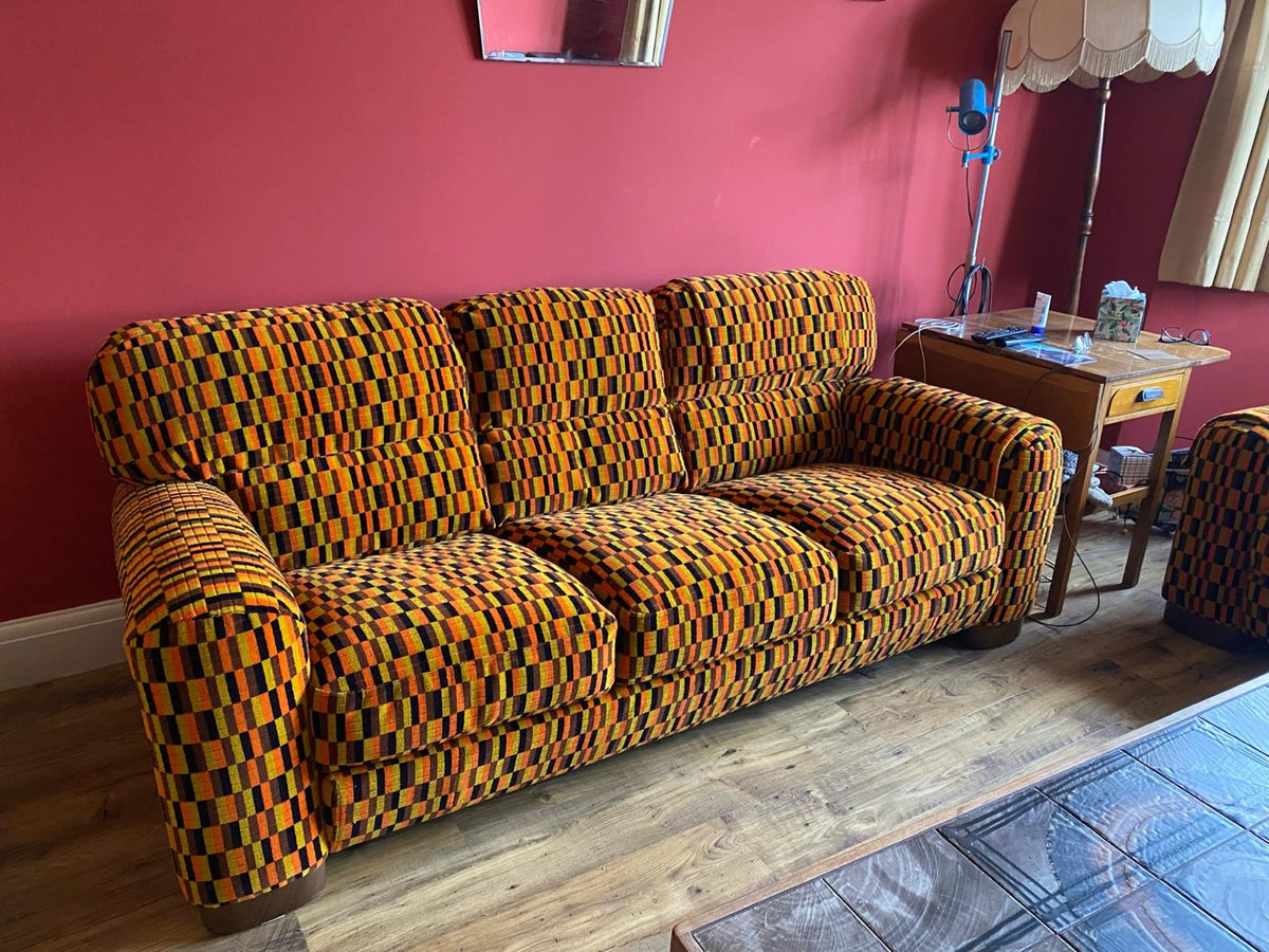 Misha Black orange yellow brown moquette sofa against red wall