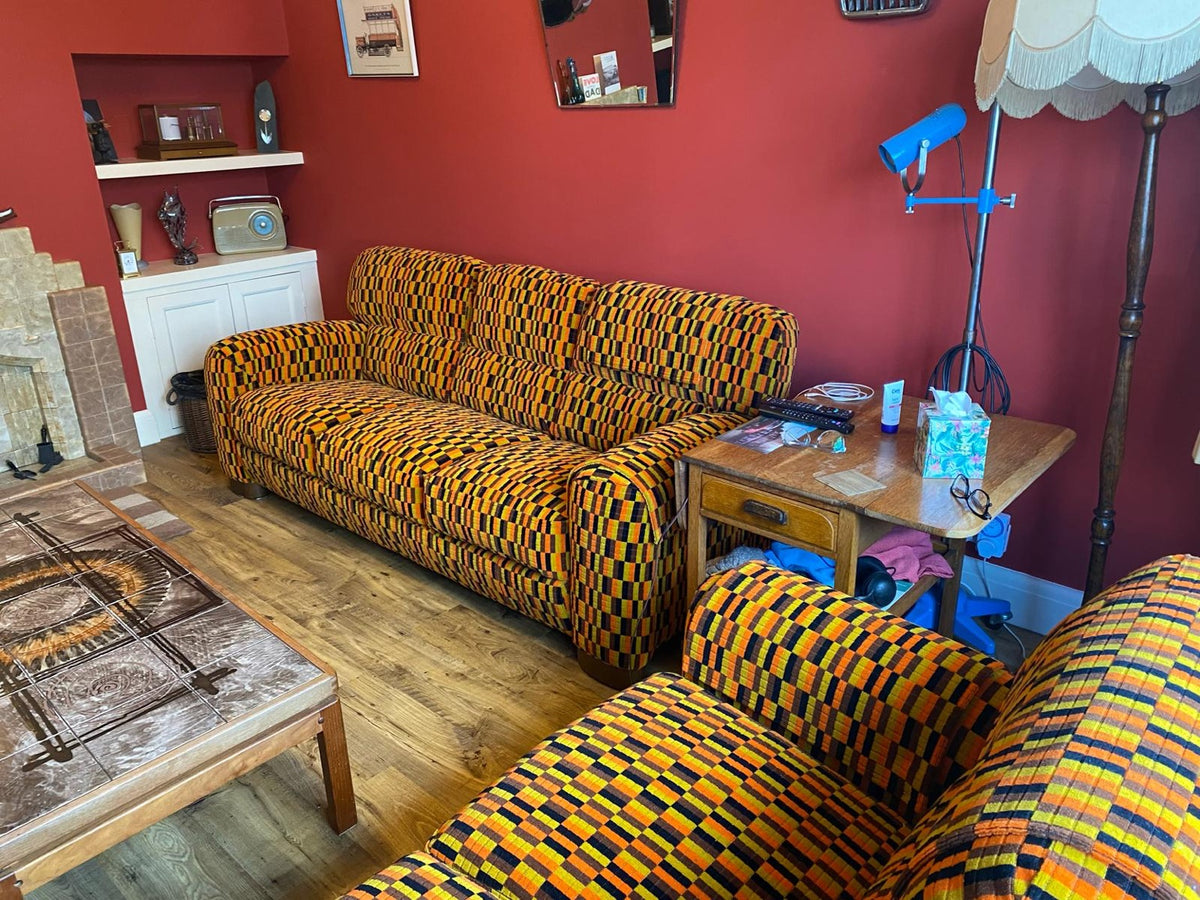 Misha Black moquette upholstered sofa in a red-walled sitting room