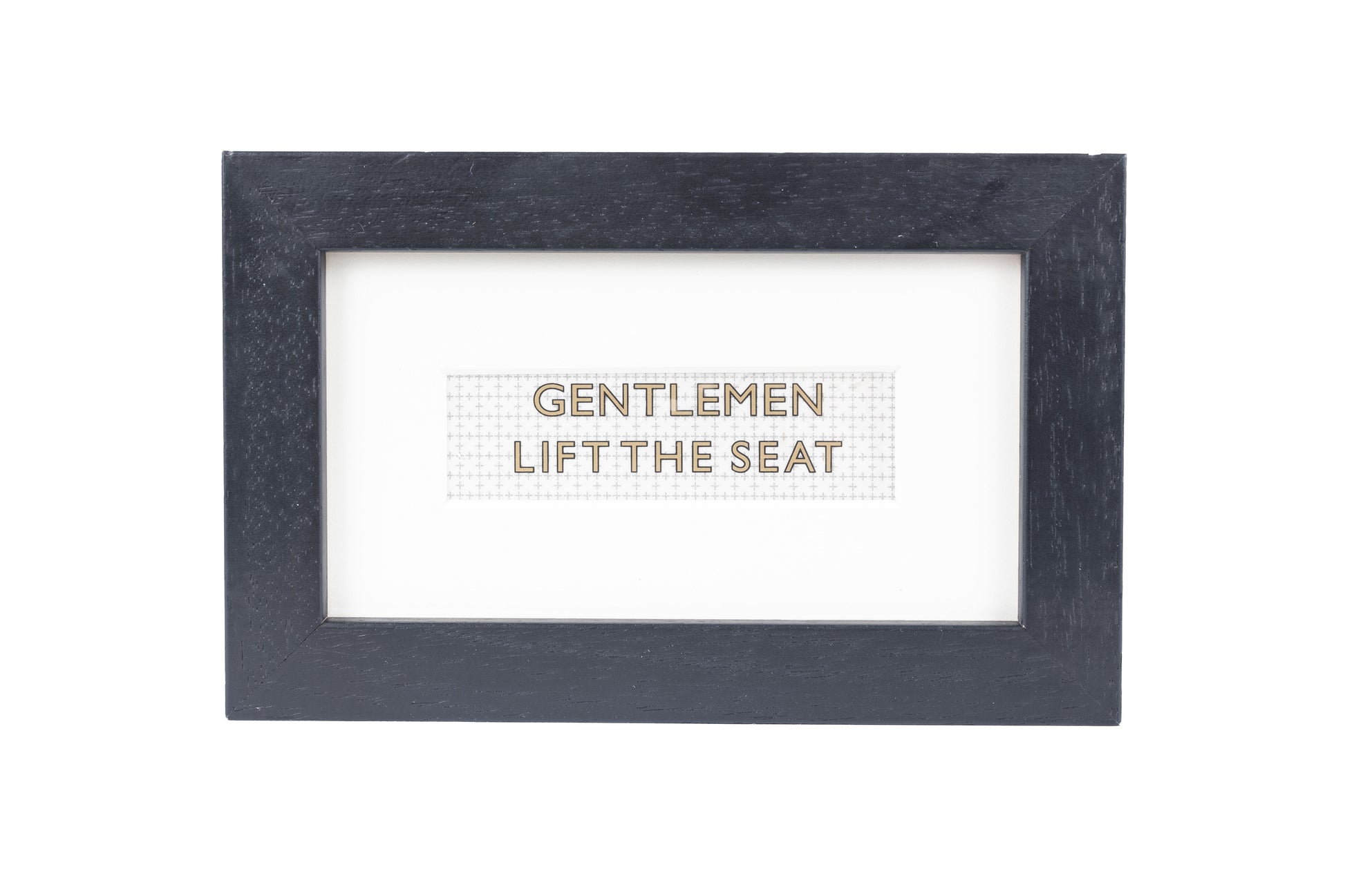 A black frame with a white background and a Gentlemen lift the seat gold text on a small Formica print background